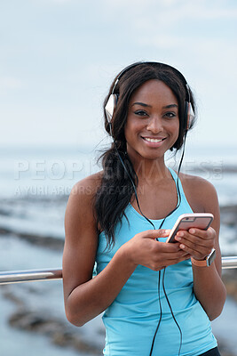 Buy stock photo Headphones, portrait and black woman at beach with music app, fitness or sports break on smartphone. Young person on smartphone in USA on social media, networking or audio streaming technology by sea