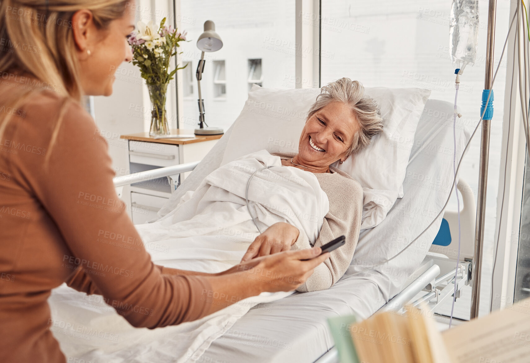 Buy stock photo Hospital visit, happy senior patient and woman visitor with phone in a medical clinic. Conversation, mobile video and happiness of a mature female with adult daughter waiting for doctor feeling calm
