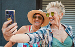 Happy, senior women and phone for selfie, profile picture or memory while bonding on vacation and urban background. Old people, friends and ladies laugh, pose and smile for picture traveling together