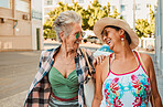 Happy, senior women and laugh in city for walking, travel and bonding on vacation and urban background. Smile, conversation and old people friends in a street for relax, walk and laughing on holiday