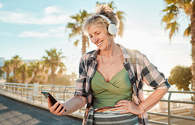 Buy stock photo Happy, music and phone with old woman at beach for streaming, freedom and summer break. Internet, technology and headphones with senior lady listening to online radio for podcast, audio and media