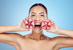 Pomegranate, woman and portrait for healthy beauty, skincare wellness and blue studio background. Happy model, face and red fruits for natural detox diet, facial nutrition and aesthetic dermatology 