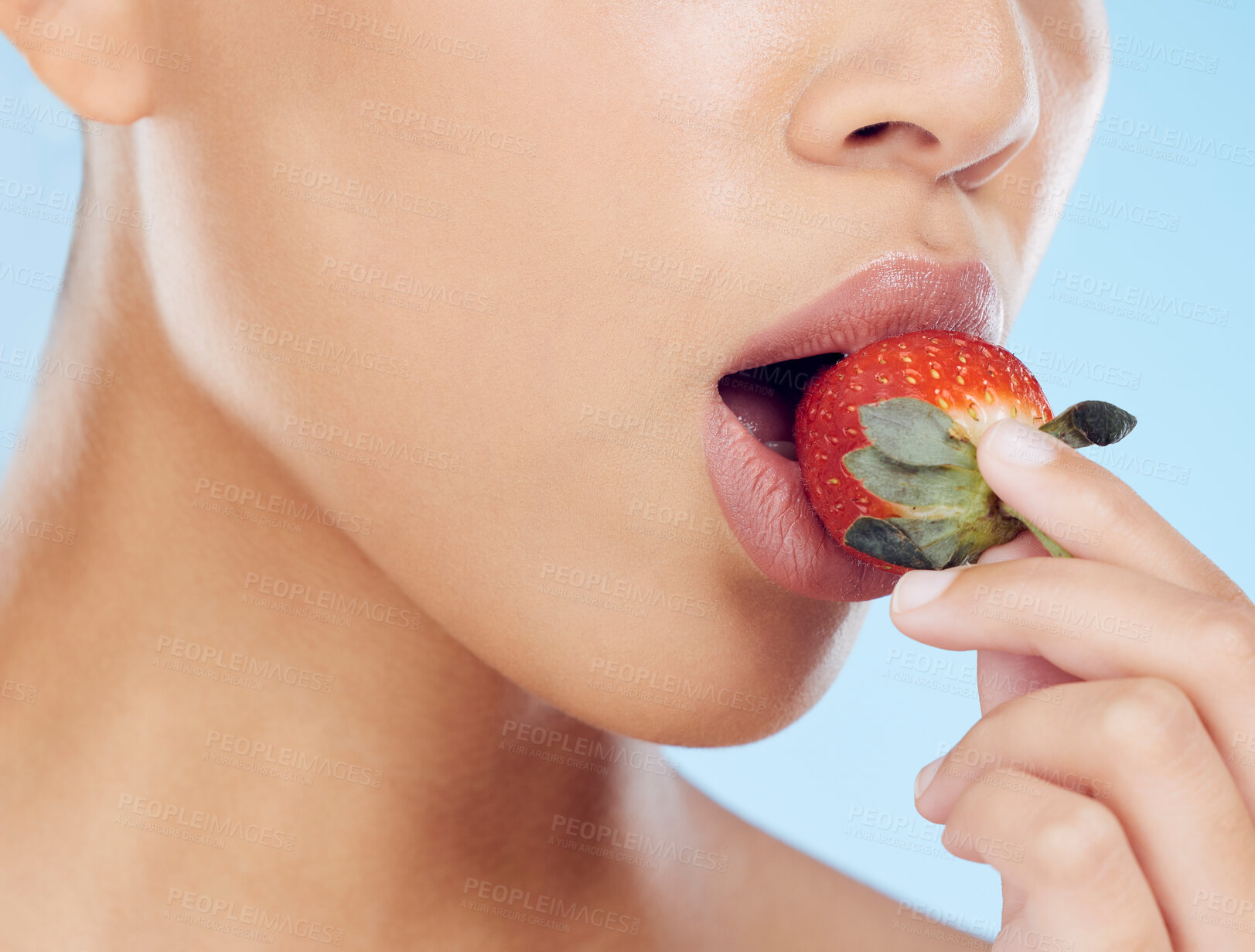 Buy stock photo Health, wellness and woman eating a strawberry in a studio for a nutritional snack or diet. Fresh food, nutrition and closeup of a female mouth enjoying a healthy red fruit by a blue background.