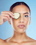 Cucumber, woman and portrait skincare for face beauty, clean wellness diet and blue studio background. Model, eyes and green fruits cosmetics for detox, facial nutrition or healthy aesthetic benefits