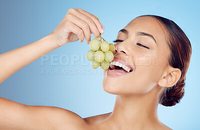 Buy stock photo Skincare, grapes and woman in studio for wellness, detox or organic treatment on blue background. Fruit, snack and girl model with relax during beauty, routine and happy with raw product isolated