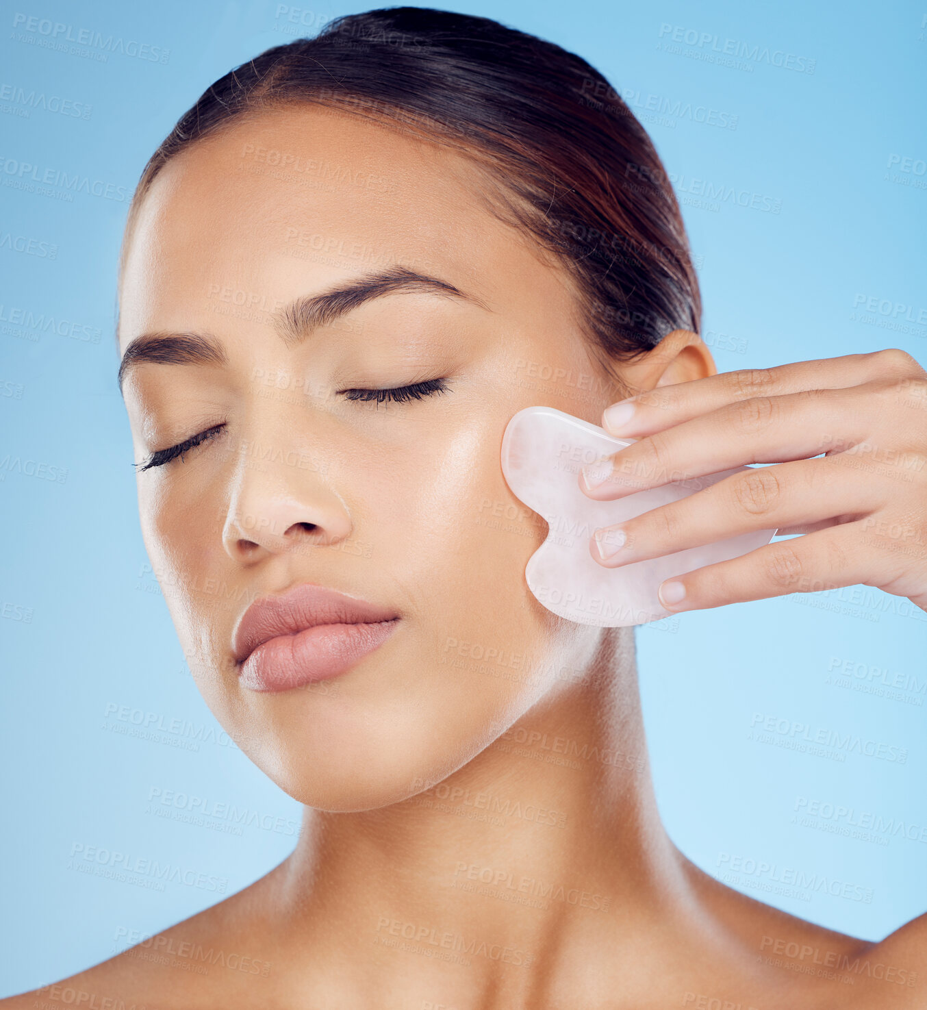 Buy stock photo Woman, beauty and face massage with gua sha, facial product or aesthetic skincare in studio. Young model, crystal stone tools and wellness for natural cosmetics, rose quartz dermatology or body salon