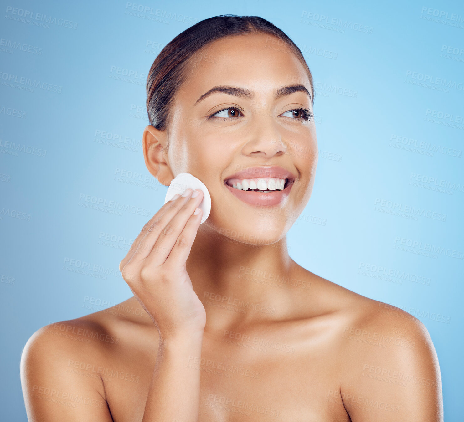 Buy stock photo Skincare, beauty and woman with cotton pad on face, smile and makeup or dirt removal with luxury skin product in studio. Dermatology, cosmetics and facial for happy model isolated on blue background.