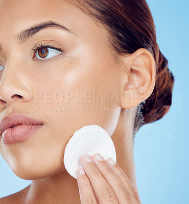 Buy stock photo Beauty, cotton pad and face, woman removing makeup or dirt with luxury skin product in studio. Dermatology, cleaning cosmetics and facial skincare spa treatment for model isolated on blue background.