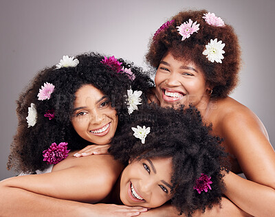 Friends, hair care and portrait of black women with flowers in studio  isolated on a gray background. Floral cosmetics, organic makeup and face of  group of girls with flower for beauty and