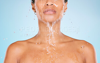 Buy stock photo Face, water and cleaning with a black woman in studio on a blue background for hygiene or hydration. Splash, shower and bathroom with a young female washing her body for natural skincare or wellness