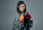 Woman, fists and pride colors in protest for gay, LGBTQ or human rights against gray studio background. Portrait of female activist standing ready in fighting pose for equality or sexuality on mockup