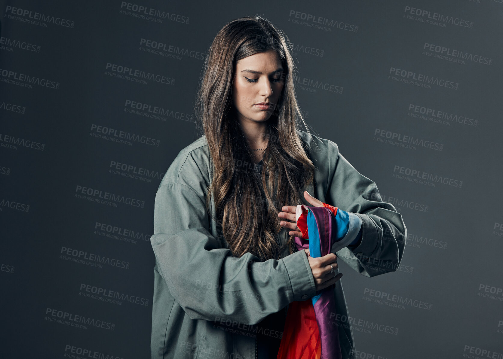 Buy stock photo Protest, LGBTQ and woman with flag in studio wrapping it on hand for human rights and equality. Empowerment, sexuality and female political activist with bisexual material isolated by gray background