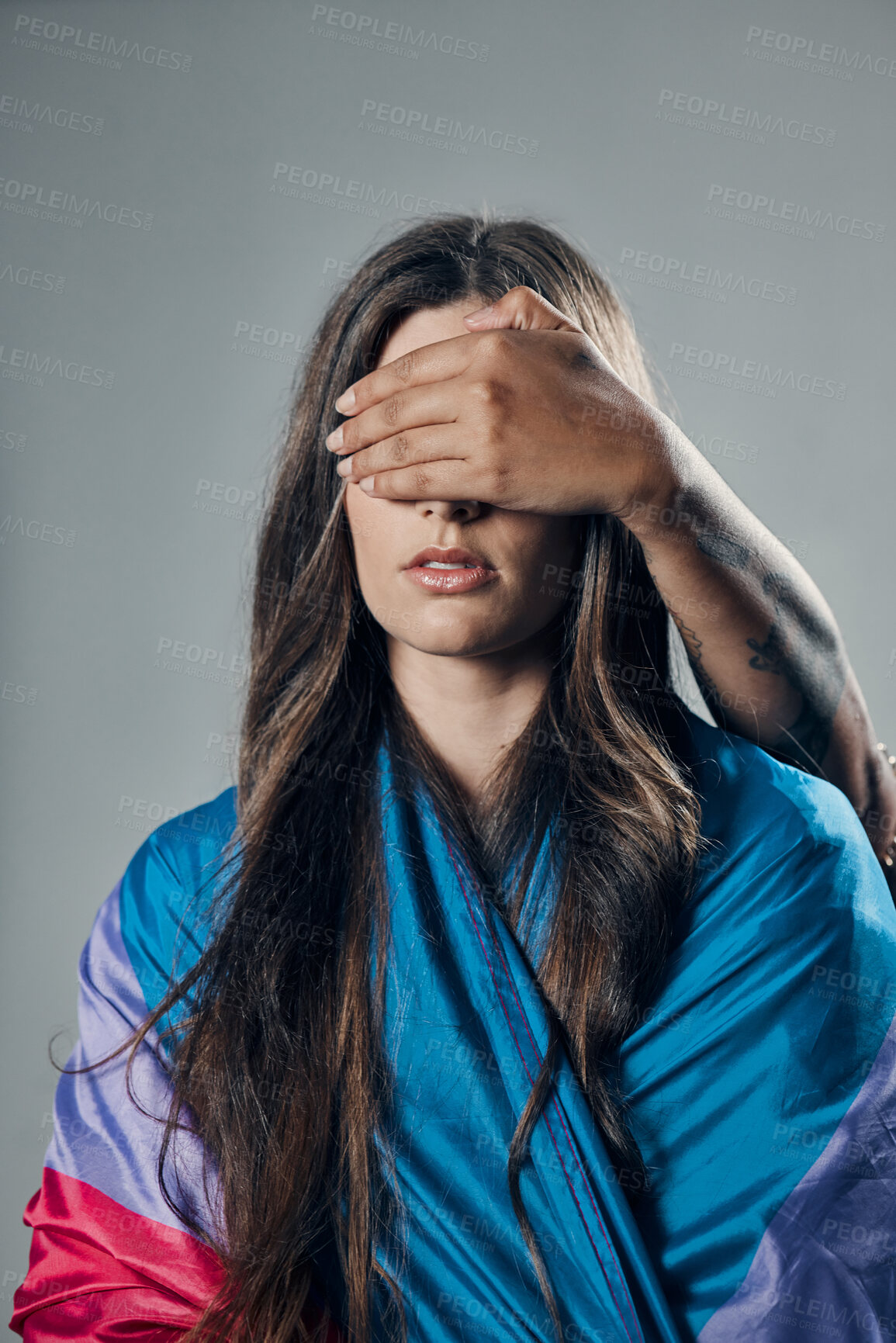 Buy stock photo Surprise, cover and woman with bisexual flag isolated on a grey studio background. Love, freedom and girl in support of LGBT community with person covering eyes to be surprised for pride on backdrop