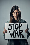 War, stop and sad woman with a sign as a voice isolated on a grey studio background. Protest, crime and girl with a board against conflict, violence and danger with an opinion in Russia on a backdrop