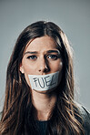 Woman, face and tape on mouth for fuel prices, ecumenic struggle or financial crisis against gray studio background. Portrait of female activist with covered lips in silence, speech or voice message