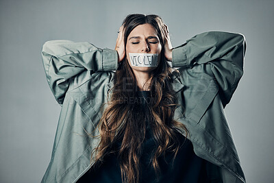 Buy stock photo Woman, protest and tape on mouth in fear for cold war, armageddon or doomsday against gray studio background. Female activist with hands on head and message to stop or end global violence in society