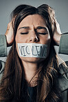 Woman, protest and tape on mouth in fear for cold war, armageddon or doomsday against a gray studio background. Female activist face with hands on head and message to stop or end global violence