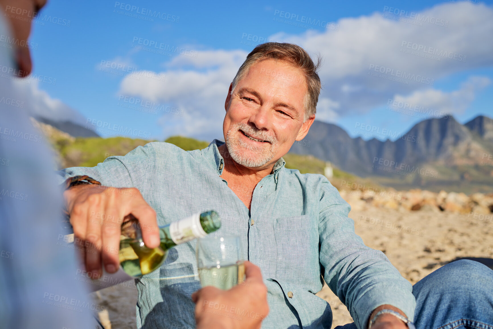 Buy stock photo Love, wine and happy with old couple on beach for celebration, anniversary and romantic date. Smile, relax and sunset with man pouring champagne for woman for vacation, summer break or travel holiday