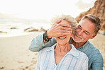 Love, happy and surprise with old couple on beach for anniversary, celebration and vacation. Travel, relax and smile with senior man cover eyes of woman for retirement, summer and support in nature