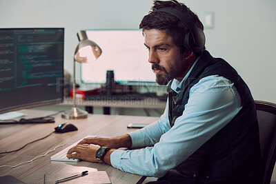 Buy stock photo Headphones, programmer and man typing on computer, coding or programming at night. Information technology, thinking and male developer or coder working on software while streaming music or podcast.