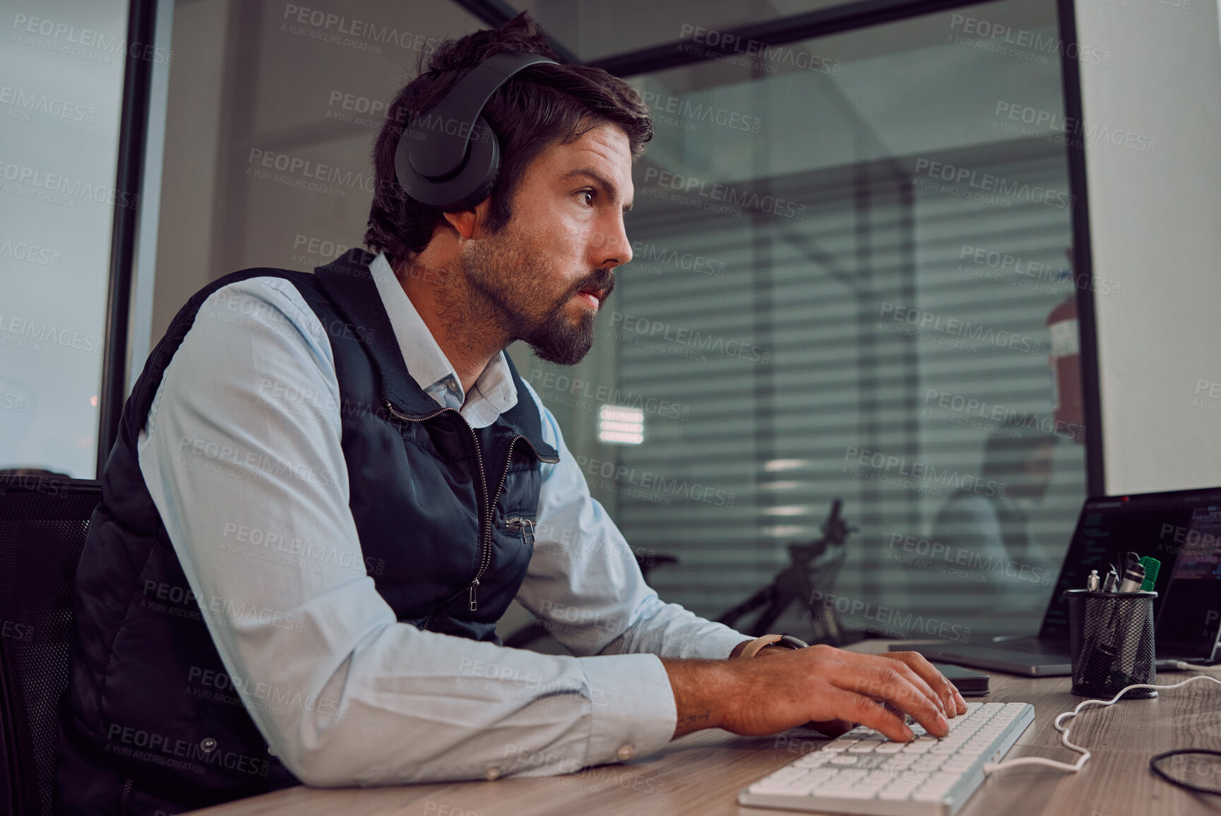 Buy stock photo Headphones, programmer keyboard and man typing, coding or programming online at night. Information technology, computer and male employee or coder working on software while streaming music or radio.