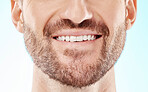 Teeth, smile and mouth of a man for dental care isolated on a blue background in a studio. Beard, happy and model showing results from whitening of tooth and promotion of an oral hygiene treatment