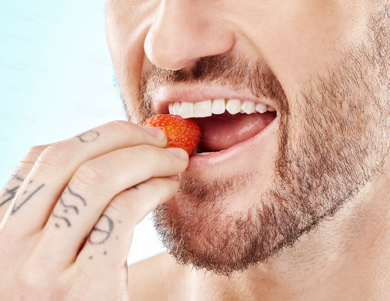 Buy stock photo Health, eating and strawberry with mouth of man for diet, detox and nutrition product. Wellness, smile and teeth with model and biting fruit closeup for vitamin c, glow and fiber in blue background