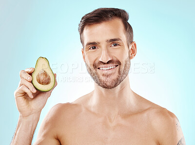 Buy stock photo Man, skincare and studio portrait with avocado for health, nutrition and cosmetic wellness by blue background. Happy young model, fruit and healthcare for natural detox, facial skin glow or aesthetic