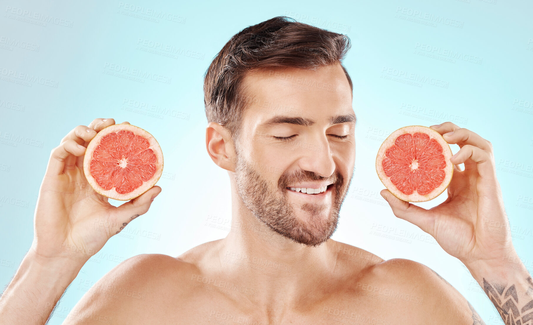 Buy stock photo Man, skincare and grapefruit in studio for health, nutrition and cosmetic wellness by blue background. Happy young model, hands and fruit for vitamin c in natural detox, facial skin glow or aesthetic