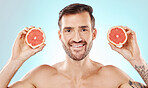 Man, skincare and studio portrait with grapefruit for health, nutrition and cosmetic wellness by blue background. Young model, fruit and vitamin c for natural detox, facial skin glow and aesthetic