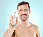 Beauty, portrait and man with perfume in a studio with a hygiene, wellness and clean routine. Health, smile and happy male model with a fresh cologne or fragrance isolated by a blue background.