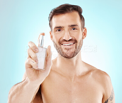 Buy stock photo Beauty, portrait and man with perfume in a studio with a hygiene, wellness and clean routine. Health, smile and happy male model with a fresh cologne or fragrance isolated by a blue background.