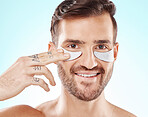 Face, skincare and man with eye patches in studio isolated on a blue background. Beauty, portrait and male model with  pad product for dermatology, cosmetics and facial treatment, wellness and health