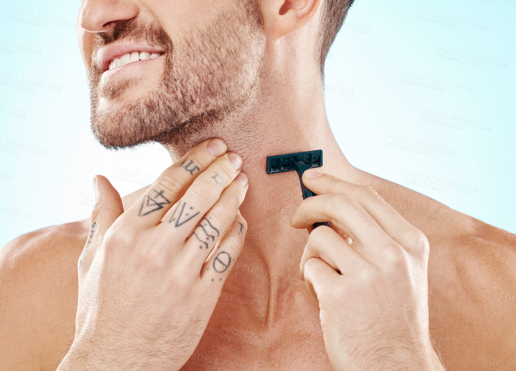 Buy stock photo Hands, shave and beard with a man grooming in studio on a blue background for skincare or hygiene. Shaving, tattoo and neck with a male in the bathroom for hair removal as part of a morning routine