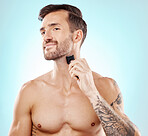 Beard portrait, man and shaving with trimmer in studio isolated on a blue background for hair removal. Haircare, grooming and male model with electric shaver to shave for hygiene, health and wellness