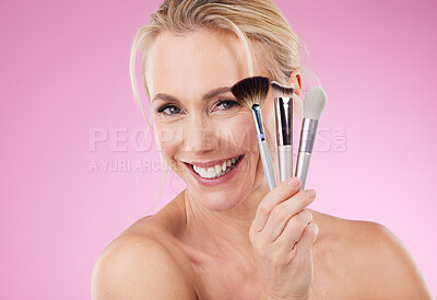 Buy stock photo Portrait, makeup and brushes with a mature woman in studio on a pink background to promote a cosmetic product. Face, happy and cosmetics with an attractive older female posing for beauty treatment