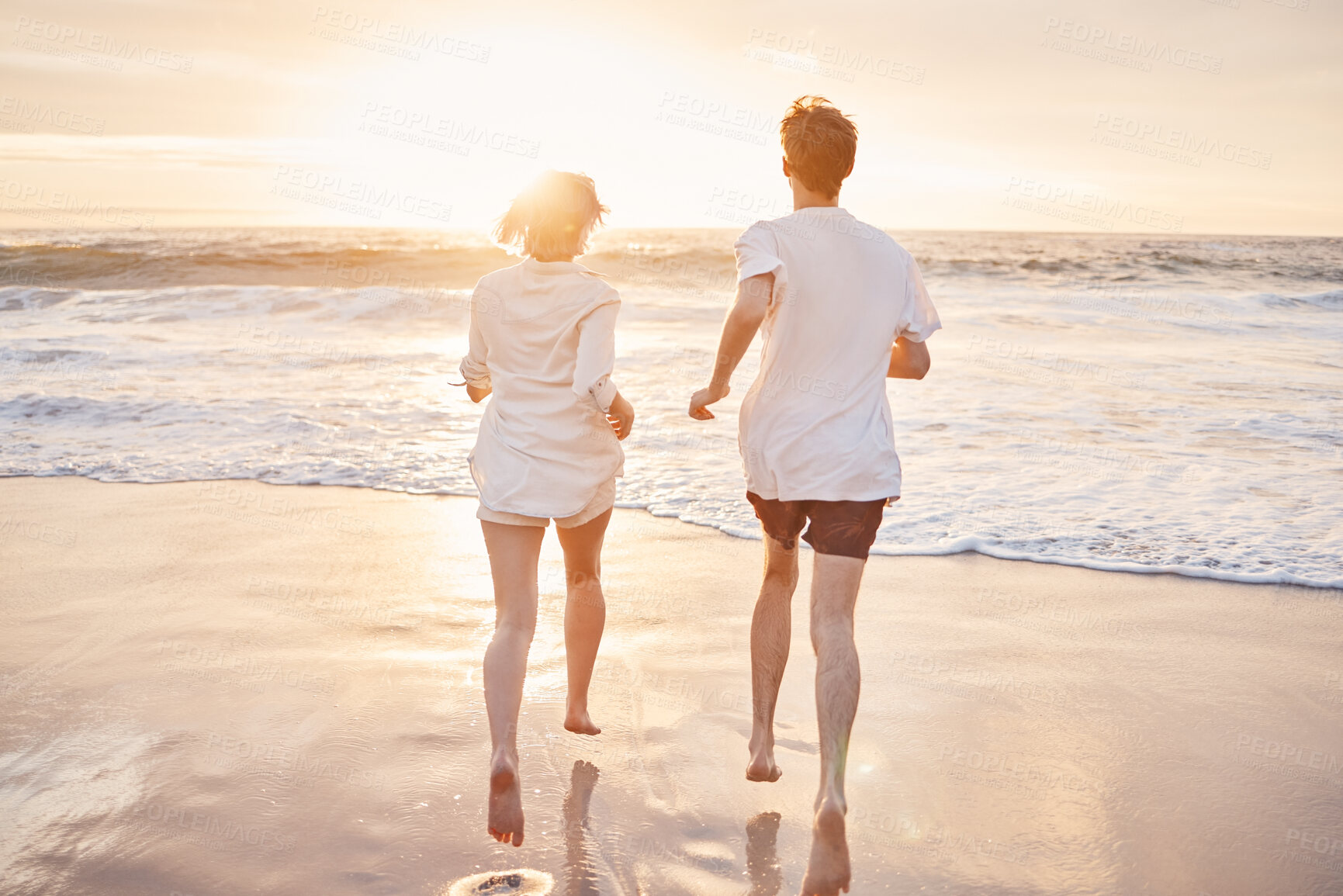 Buy stock photo Couple at beach, running to ocean with travel and freedom outdoor, love and care in relationship with youth. Care free at sunset, nature and sea waves with young people back view on holiday in Hawaii