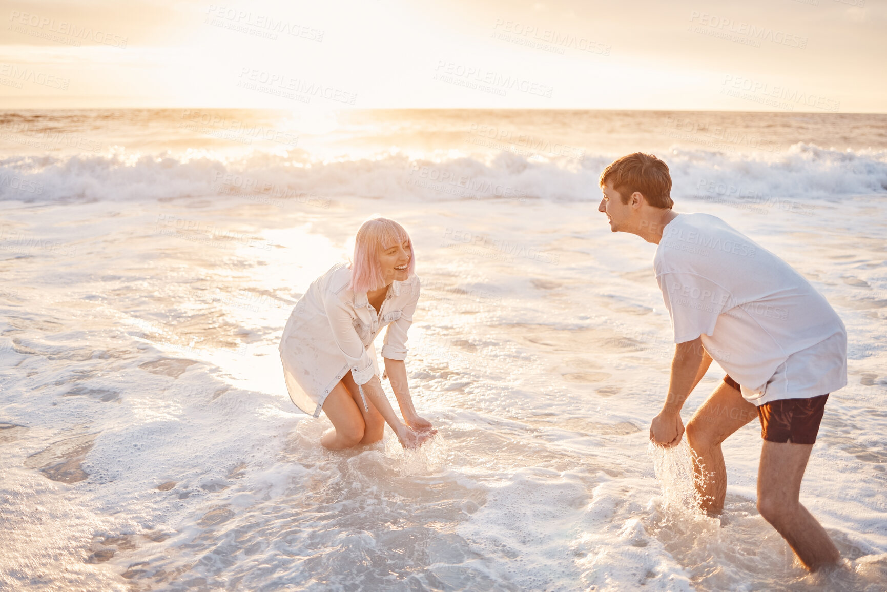 Buy stock photo Couple at beach, splash in water with sea, travel and freedom outdoor, love and care in relationship with youth. Cafe free at sunset, nature and ocean waves with young people on holiday in Hawaii