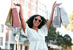 Shopping, bags and happy woman with sunglasses in the city for a sale, discount or promotion. Happiness, smile and portrait of female customer enjoying retail fashion shop spree in the street in town
