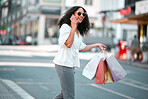 Black woman, phone call and shopping bags walking in the city with smile for conversation or discussion. Happy African American female shopper holding gifts and crossing street on smartphone in town