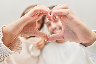 Buy stock photo Hands, heart and love with a couple in their home together, bonding for romance or affection while dating. Hand sign, romantic or marriage with a man and woman sitting in a house living room closeup
