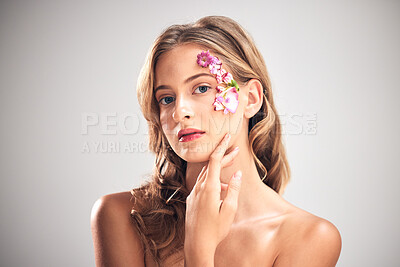 Buy stock photo Flower art, beauty and portrait of woman for natural cosmetics, skincare wellness and makeup in studio. Spring, creative and girl with petal on face for spa aesthetic, luxury facial and cosmetology