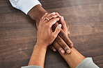 Holding hands, support and trust with people, closeup on wood table with communication, relationship and solidarity. Wellness, mental health or praying with counselling or worship, help and comfort