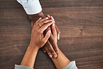 Holding hands, support and trust with people, help and closeup on wood table with communication and relationship Wellness, mental health or praying with counselling or worship, solidarity and empathy