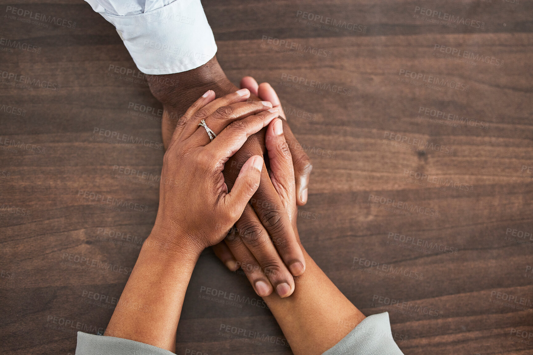 Buy stock photo Holding hands, support and trust with people, help and closeup on wood table with communication and relationship. Above, mental health or praying with counselling or worship, solidarity and empathy