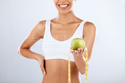 Buy stock photo Detox, apple and tape measure with a fitness black woman in studio on a gray background for healthy eating. Exercise, fruit and wellness with a female posing to promote a lifestyle of health or diet