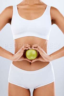 Buy stock photo Nutrition, apple and woman hands on stomach in heart shape for digestion, detox diet and studio background. Fruits, wellness and healthy abdomen body with care, love and lose weight for strong gut