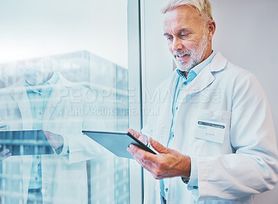 Buy stock photo Tablet, doctor and medical professional doing online health or telehealth connected to internet, web or wifi in an office building. GP, senior and elderly healthcare worker working by  window typing