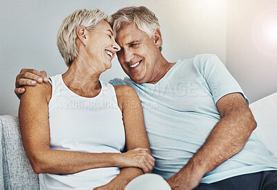 Buy stock photo Love, laughing and retirement with a senior couple sitting in the living room of their home together. Happy, smile or relax with a mature man and woman joking while bonding on the couch in a house