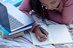 Student, studying and woman writing notes from research assignment for college or university academic education. Park, learning and African American young female lying down on blanket with a textbook